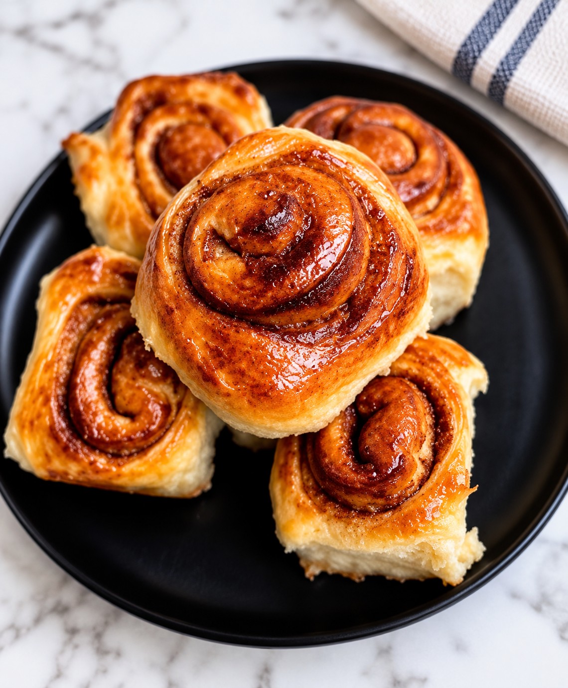 Golden cinnamon rolls on a black plate